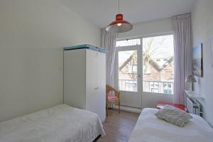 een slaapkamer met 2 bedden en een groot raam bij Residence de L'Europe - Baddomburg in Domburg