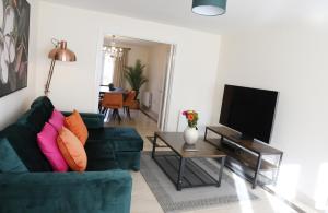 a living room with a green couch and a television at Spacious home with office and double driveway & FREE Wifi By ULTIMATE HOMES AWAY in Winnersh