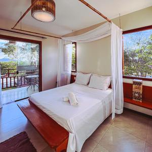 1 dormitorio con 1 cama blanca grande y balcón en Chalés Terraviva, en Pirenópolis