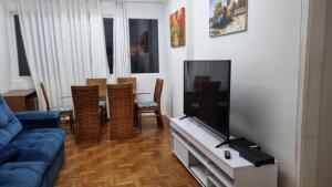 uma sala de estar com um sofá azul e uma televisão de ecrã plano em Apartamento 3 quartos em Copacabana no Rio de Janeiro
