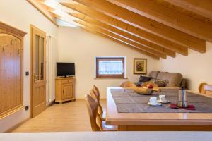 a dining room with a table and a couch at Casa Rossetti Big in Pozza di Fassa