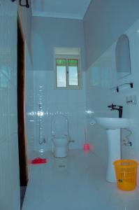 a white bathroom with a toilet and a sink at Kinindo Light Hotel in Bujumbura