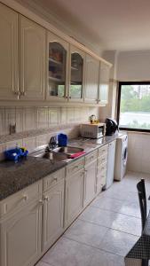 a kitchen with white cabinets and a sink at Happyhouse in Algueirão - Mem Martins