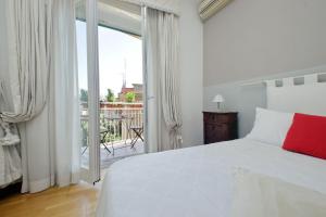 Habitación blanca con cama y balcón. en Confortevole appartamento vicino Ponte Milvio en Roma