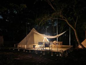 Zelt mit einem Tisch und Stühlen auf einer Holzterrasse in der Unterkunft COUSCOUS Glamping Manazuru in Manazuru