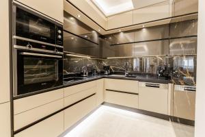 a kitchen with white cabinets and black appliances at Vivian's Luxury Suite in Monemvasia