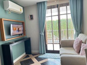 a living room with a couch and a tv at Espana Condo Jomtien Pool access By Aey in Jomtien Beach