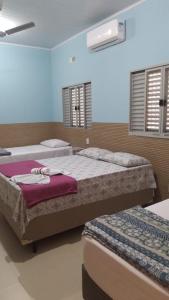 two beds in a bedroom with two windows at Hotel Vitoria Andradina in Andradina