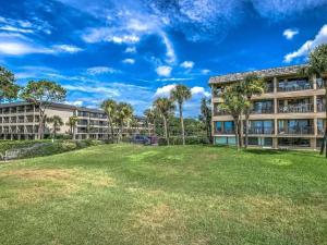 um grande quintal em frente a um edifício com palmeiras em Beachfront Condo with Ocean View em Hilton Head Island