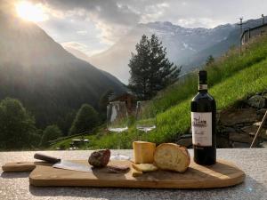 a bottle of wine and some cheese and wine glasses at Baita Chalet La Masun in Chiesa in Valmalenco