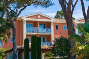 an orange building with trees in front of it at Lagrange Vacances Le Domaine des Grands Pins in Saint-Raphaël