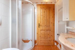 a bathroom with a shower and a wooden door at Casa Titol Ami in Pozza di Fassa