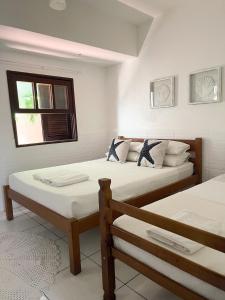 two twin beds in a room with a window at Peixe Crew Centro in Búzios
