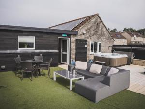 a patio with a couch and a table and a hot tub at Crossways in Wells