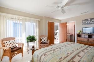 a bedroom with a bed and two chairs and a television at SC214-Tastefully decorated 3 bedroom 2 bath condo in Edgewater