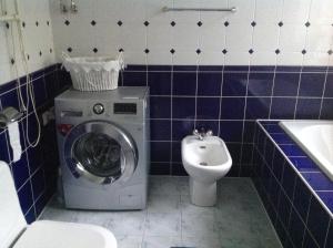 a bathroom with a washing machine and a toilet at Apartment on Riepnieku Street in Riga