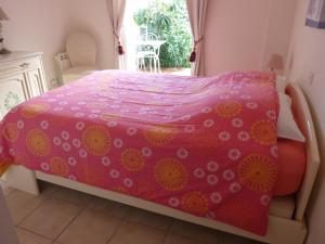 - une chambre avec un lit et une couverture rose dans l'établissement A l'ombre du figuier, à Lorgues
