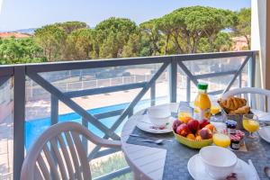 - une table avec un bol de fruits et de jus sur un balcon dans l'établissement Lagrange Vacances Le Domaine des Grands Pins, à Saint-Raphaël