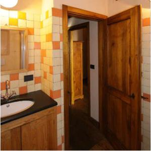 ein Badezimmer mit einem Waschbecken und einer Holztür in der Unterkunft Agririfugio Molini in Camogli