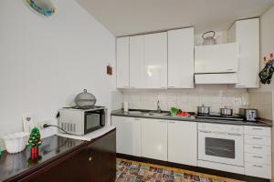 Una cocina con gabinetes blancos y un microondas. en Studio Saturno 23 in the city center - Happy Rentals, en Sauze dʼOulx
