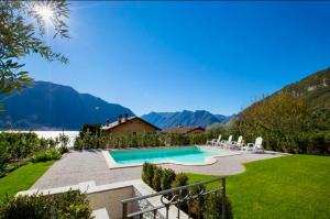 un cortile con piscina, sedie e montagne di La Bella Ossuccio a Ossuccio