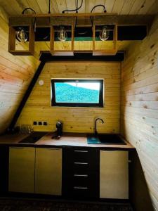 eine Küche im Dachgeschoss mit einem Waschbecken und einem Fenster in der Unterkunft Macko’s cabin in Băile Tuşnad