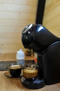 eine Kaffeemaschine auf einem Tisch mit zwei Tassen Kaffee in der Unterkunft Macko’s cabin in Băile Tuşnad