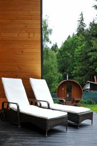 2 sillas sentadas en un porche con bañera en Macko’s cabin, en Băile Tuşnad