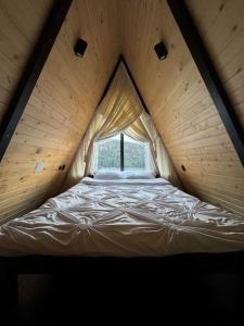Bett in einem Holzzimmer mit Fenster in der Unterkunft Macko’s cabin in Băile Tuşnad