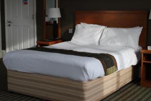 a large bed with a wooden headboard in a hotel room at Fairway Inn in Manchester