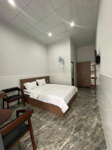 een slaapkamer met een bed, een tafel en een ventilator bij Nam Anh Hotel in Bao Loc