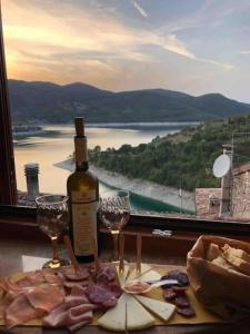 a bottle of wine and glasses on a table with a window at La Dimora del Turano in Castel di Tora