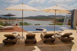 a patio with chairs and umbrellas next to a pool at Casa na represa in Vargem