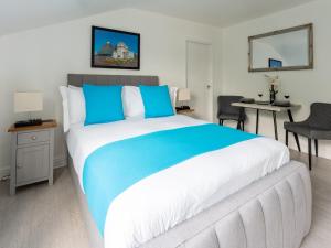 um quarto com uma cama grande com lençóis azuis e brancos em Tettenhall Lodge Studio em Wolverhampton