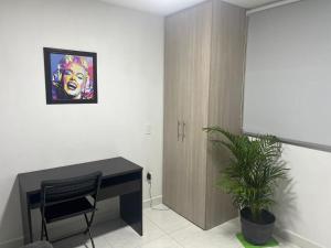 Habitación con escritorio y una pintura en la pared. en Sabaneta Central Nómadas digitales Wi-Fi 201 en Sabaneta