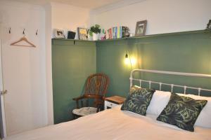 a bedroom with a bed with a green headboard and a chair at Goodwood Events House with Garden & Parking - Chichester Holiday Properties in Chichester