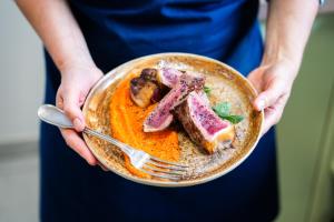 a person holding a plate of food with meat on it at La Pépite in Margut