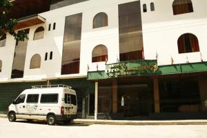 una furgoneta blanca estacionada frente a un edificio en Hotel Oro Verde & Suites, en Iquitos