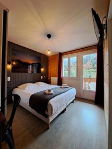 a bedroom with a bed and a large window at Hôtel Les Mouflons in Le Mont-Dore