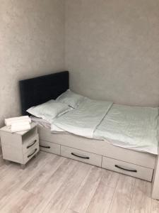 Schlafzimmer mit einem Bett mit weißer Bettwäsche und Holzböden in der Unterkunft Lux апартаменты ЖК 7я in Astana