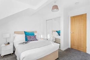 sypialnia z dużym białym łóżkiem z niebieskimi poduszkami w obiekcie Chandlers Walk modern comfy family home in Exeter w mieście Exeter