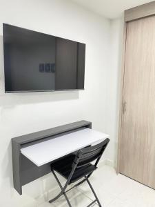 a white desk with a television on a wall at Sabaneta Central Nómadas digitales Wi-Fi 202 in Sabaneta