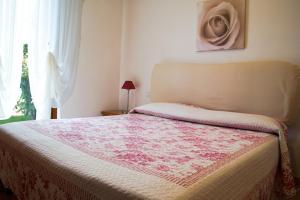 a bedroom with a bed with a pink blanket on it at Poggio Degli Olivi in Saturnia