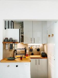 uma cozinha com armários brancos e uma bancada em Jolie studio Parisien em Paris
