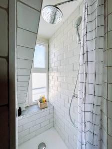 ein weißes Bad mit einer Dusche und einem Fenster in der Unterkunft Jolie studio Parisien in Paris