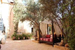 a tent with a red couch under a tree at Riad El Koudia in Douar el Koudia