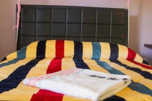 a bed with a colorful blanket and towels on it at Buvuma Island Beach Hotel in Jinja
