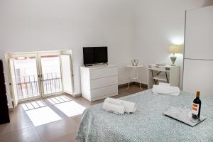 a white living room with a bottle of wine on a table at Ruggero Settimo - Holiday Houses in Catania