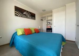 ein Schlafzimmer mit einem blauen Bett und bunten Kissen in der Unterkunft Departamento Sor Vicenta in Los Ángeles