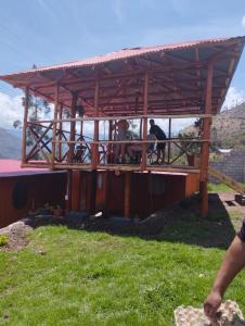 een houten paviljoen met twee personen eronder bij the wooden house choquequirao in Cachora